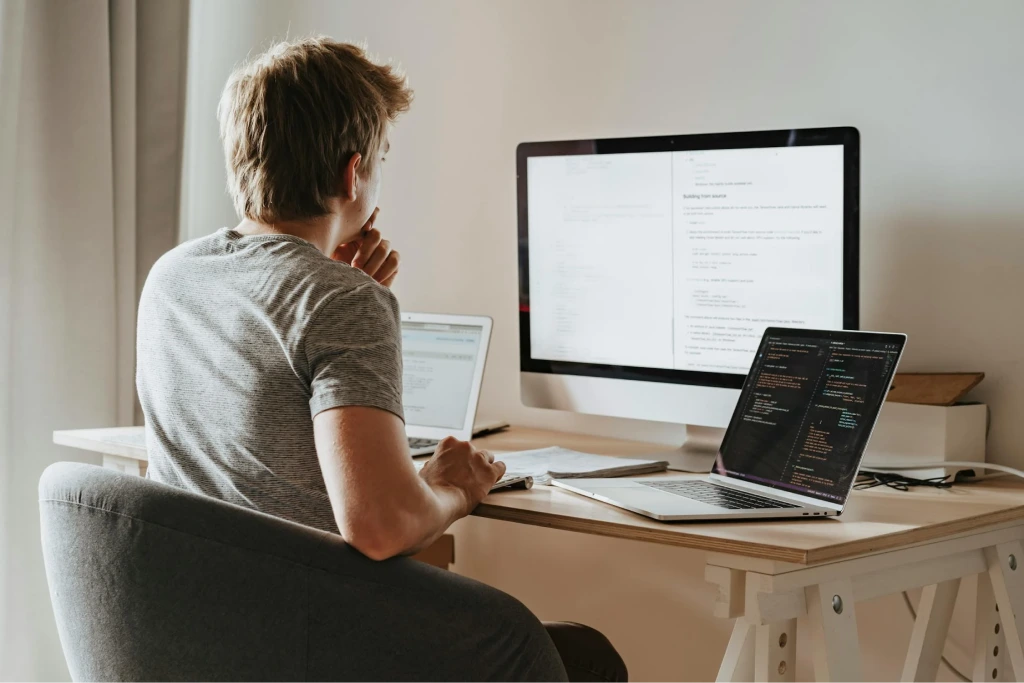 a Freelance Website Developer sitting at a desk with two computers